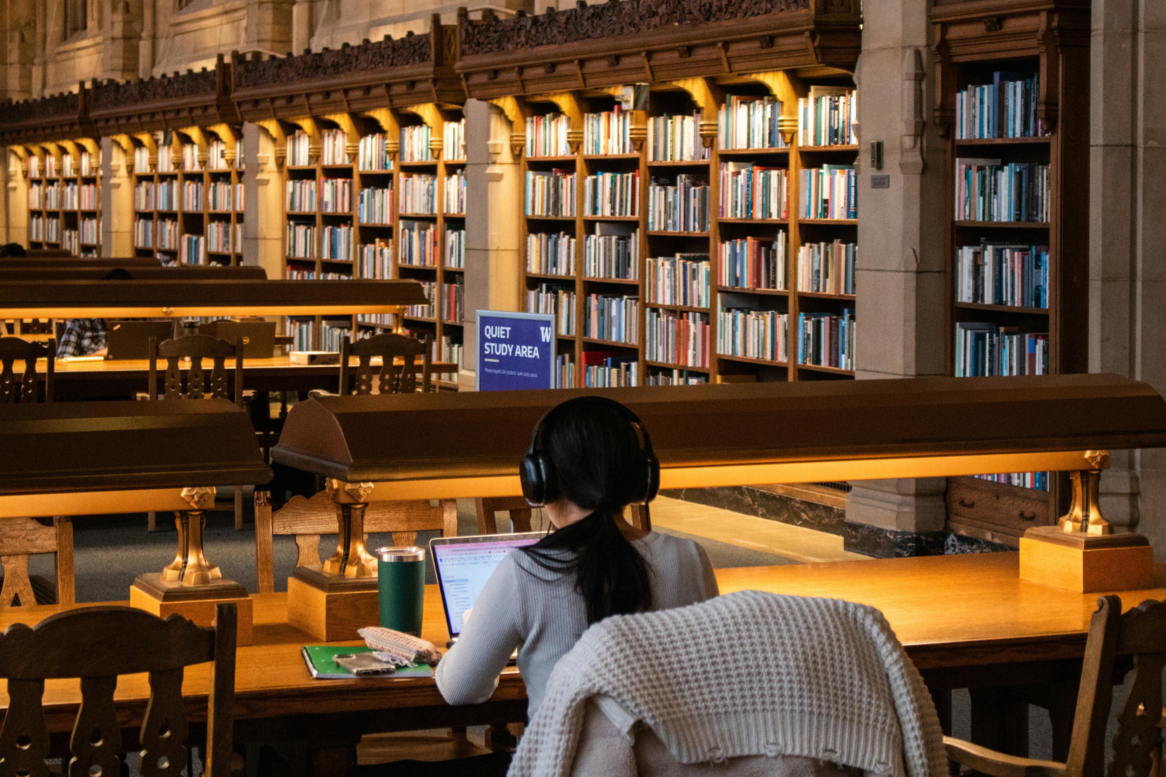 A student studying with a laptop in a grand university library